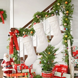 Close-up of white cable knit Christmas stockings hanging on a festive staircase