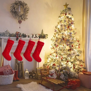 Close-up of four red knitted Christmas stockings with cable patterns hanging on a fireplace