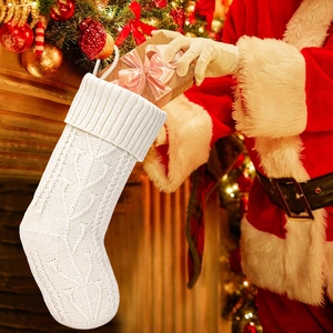 Macro view of cream knit Christmas stocking with classic cable stitch and gift box