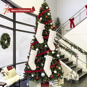 Set of 4 ivory white cable knit Christmas stockings hanging on a festive decorated tree