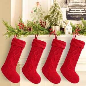 Set of 4 large red cable knit Christmas stockings hanging on a white festive fireplace