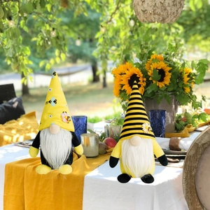 Close-up of summer bee gnomes with sunflower and striped hat on a garden table