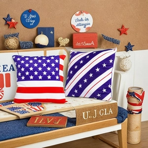Set of two US flag decorative pillows on a wooden bench with patriotic home decor