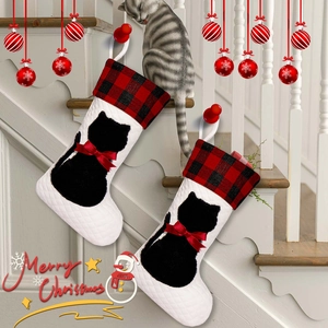 Detail of buffalo plaid Christmas stockings with black cat silhouettes on wooden stairs
