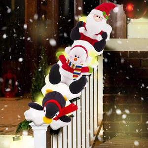 Babbo Natale, pupazzo di neve e pinguino di peluche su decorazione luminosa per scale