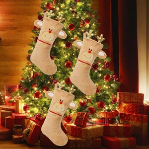 Trois chaussettes de Noël en peluche renne avec bois dorés devant un sapin festif