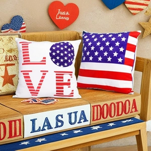 Independence Day throw pillows with USA flag design and LOVE text on wooden bench