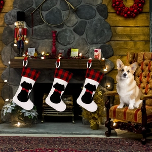 Plaid Christmas stockings featuring black dog silhouettes hung on a rustic stone fireplace