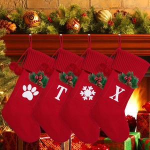 Detail of red knit Christmas stockings with white letters hanging on a cozy fireplace