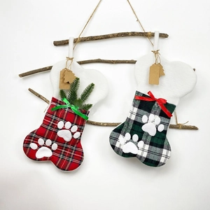 Calze di Natale a forma di osso con motivo scozzese appese a rami con fiocchi colorati