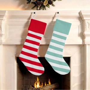 Gestrickte Weihnachtsstrümpfe mit roten, mintgrünen und weißen Streifen am Kamin hängend