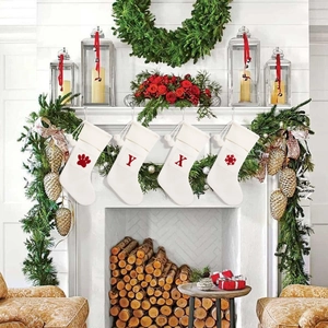Close-up of four white knitted Christmas stockings with red embroidery on a festive mantel