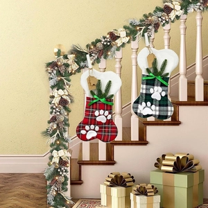 Calze di Natale a forma di osso con motivo scozzese e impronte di zampe appese