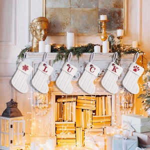Set of 6 white cable knit Christmas stockings with red LUCK embroidery on a mantel