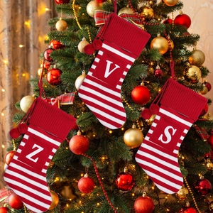 Knitted Christmas stockings with red stripes, hanging pompoms and white alphabet letters