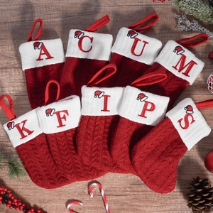 Rote Strick-Weihnachtssocken mit weißen Buchstaben-Stickereien und Festdeko