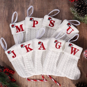 White knitted Christmas stocking ornaments with red embroidered letters and mini Santa hats