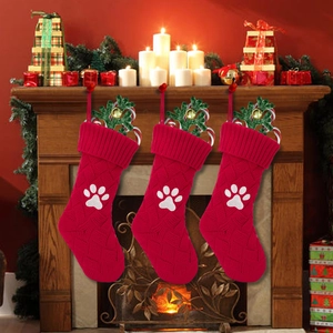 Calza natalizia in maglia rossa con ricamo di zampa bianca e decorazioni festive