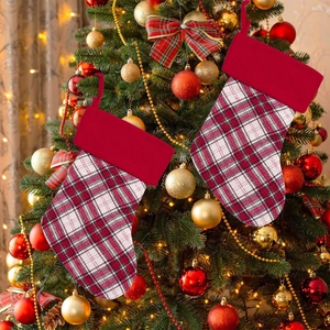 Détail de chaussettes de Noël à carreaux rouges suspendues à un sapin illuminé
