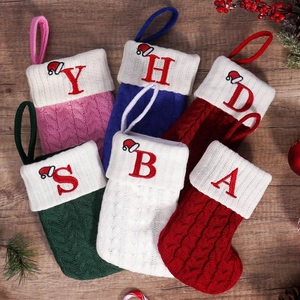Personalized cable knit Christmas stockings with embroidered letters on wood background
