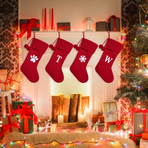 Close-up of red knitted Christmas stockings with white embroidery and plush pom-poms