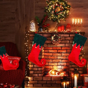 Detail of red and green velvet elf Christmas stockings with bells on a festive fireplace