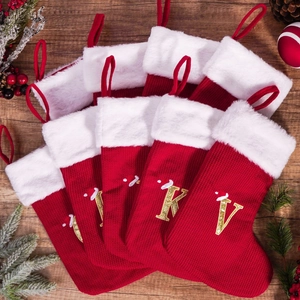 Red knit Christmas stockings with white faux fur trim and gold embroidered letters