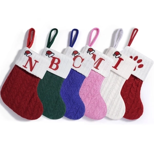 Set of cable knit Christmas stockings in red, green, blue, and white with letter embroidery