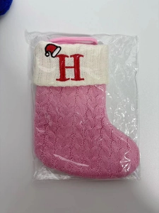 Detailed knit texture of a pink Christmas stocking featuring an embroidered red letter H