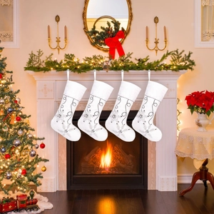 Set of four white plush Christmas stockings with silver snowflakes hanging on a fireplace