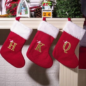 Set of three red knitted Christmas stockings with gold embroidered letters and mini hats