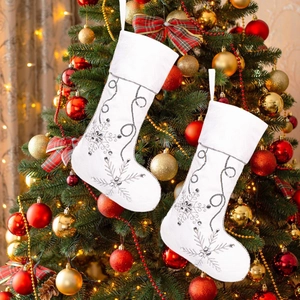 Close-up of white plush Christmas stocking with silver sequin snowflakes on a tree