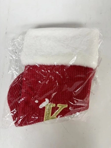 Close-up of red knit Christmas stocking with white faux fur cuff and golden letter V