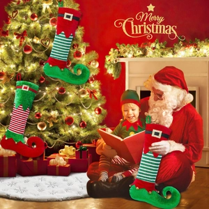 Three striped elf boot Christmas stockings with bells hanging by a festive tree