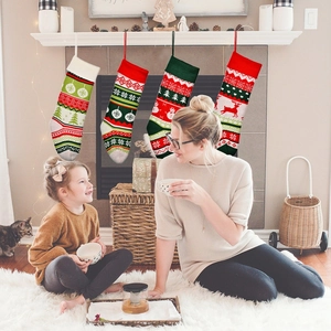 Cozy family scene showing four large knitted Christmas stockings with reindeer and trees