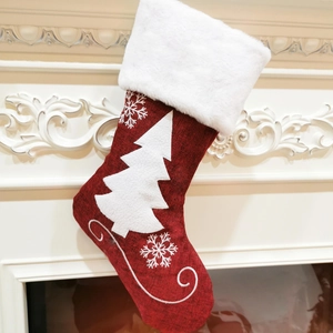 Dettaglio di calza di Natale rossa con bordo in peluche appesa a un camino bianco