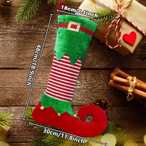 Detail of red and green elf Christmas stocking with bells and stripes on wood floor