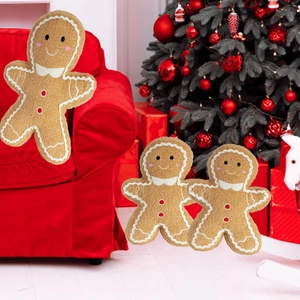 Gingerbread man plush pillow on a festive red sofa near a decorated Christmas tree