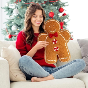 Gingerbread man plush pillow with red bow and mint buttons in a cozy Christmas scene