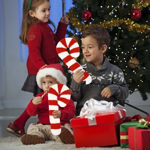 Bambini che giocano con cuscini natalizi in peluche a forma di bastoncino di zucchero