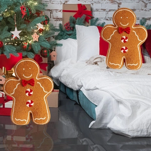 Plush gingerbread man throw pillow with red bow tie and festive Christmas tree background