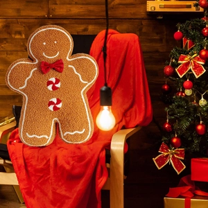 Gingerbread man plush pillow with red bow and white embroidery on a festive red chair