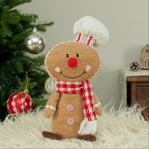 Detail view of sitting gingerbread man plush chef with festive hat and scarf decor