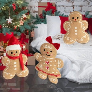 Set of three plush gingerbread man pillows with red bows on a cozy Christmas bed