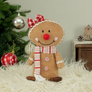Christmas gingerbread man plush doll with red bow and scarf on a cozy white rug