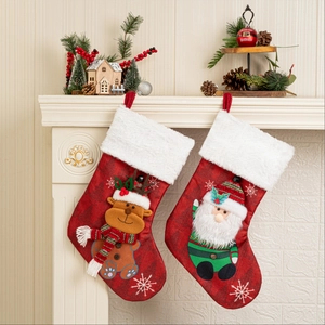 Set mit zwei roten Weihnachtsstrümpfen mit Weihnachtsmann und Rentier vor einem weißen Kamin