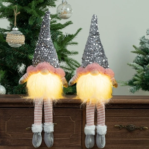 Detail of two light-up Christmas gnomes with glowing LED beards on a wooden shelf