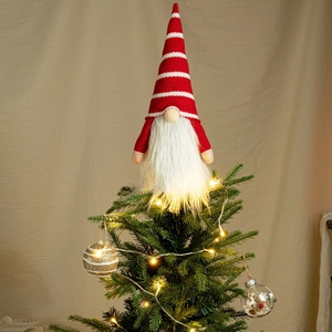 Detail of Christmas tree topper gnome with red white striped knit hat and warm LED lights