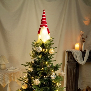 Close-up of lighted Christmas gnome tree topper with red striped knit hat and warm LED glow