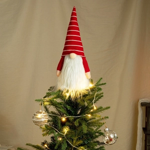 Close-up of lighted red striped gnome tree topper with LED string lights and gold baubles